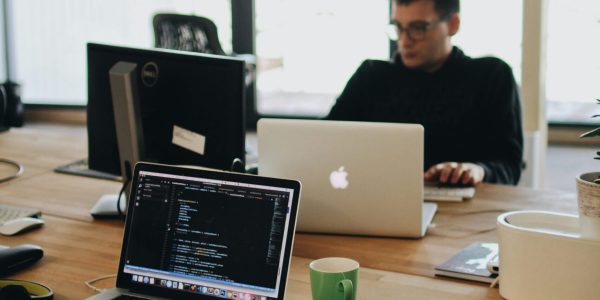 A web developer working on code in a modern office setting with multiple devices.